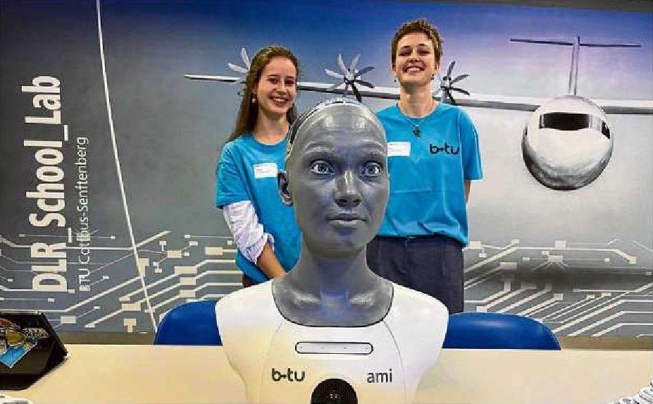 Johanna (l.) und Enya, Schülerinnen am Max-Steenbeck-Gymnasium, stellen den humanoiden Roboter Ami in Cottbus vor.