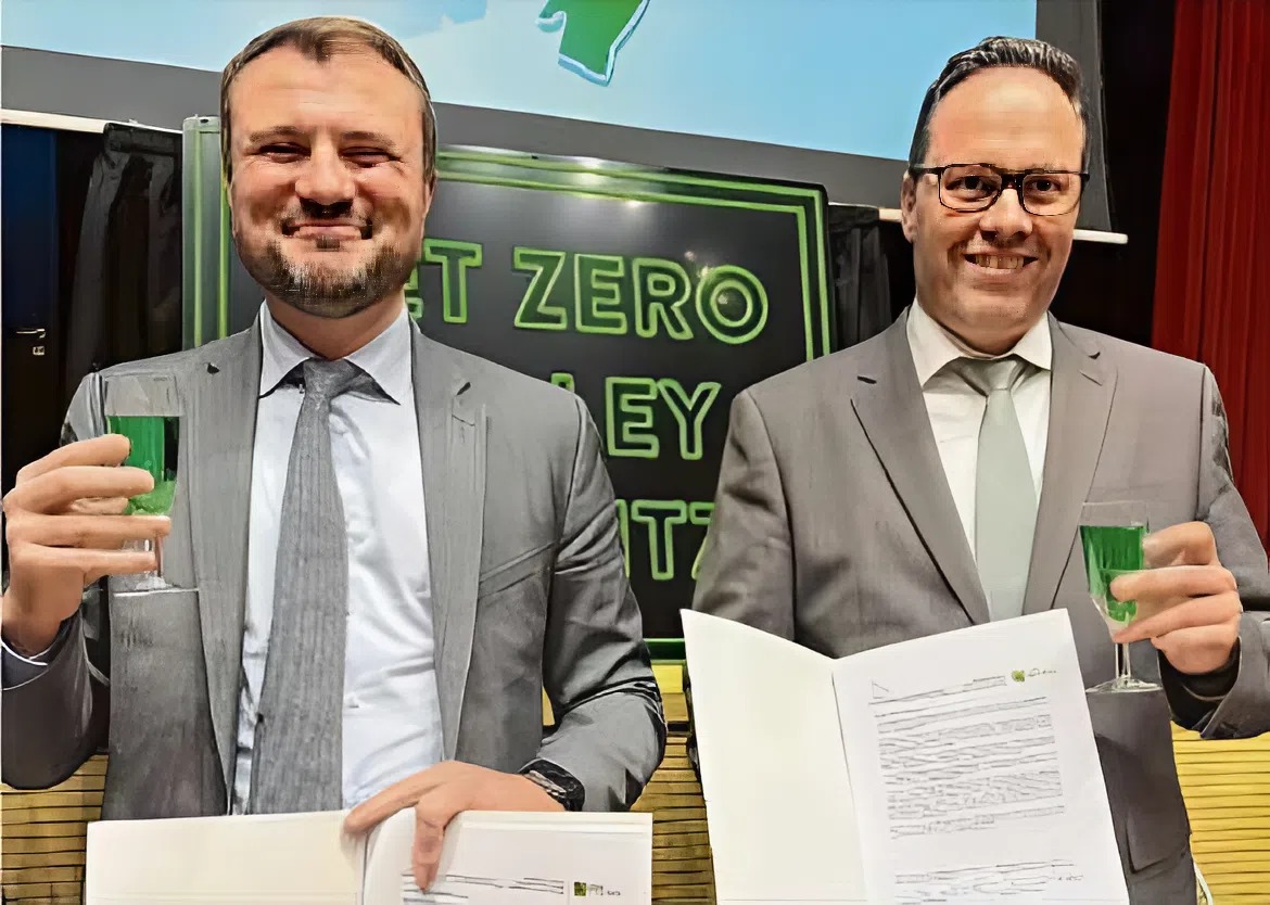 Die Wirtschaftsminister der Länder Brandenburg und Sachsen kommen frisch von den Kabinettssitzungen in Potsdam und Dresden. Daniel Keller (SPD/l.) und Dirk Panter (SPD) sind taufrischermächtigt, den Ausweisungsbeschluss für das Net Zero Valley Lausitz zu unterzeichnen. Angestoßen wird standesgemäß grün–mit Waldmeisterbrause.