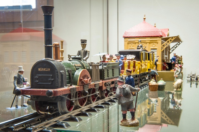 Auf der detailreichen Märklin-Anlage im Sänger- und Kaufmannsmuseum Finsterwalde herrscht reges Treiben: Während Reisende am Bahnsteig warten und im Zug Platz nehmen, fährt die Lok pünktlich aus dem historischen Bahnhof hinaus.