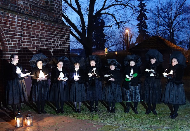 Ostersängerinnen singen am Ostermorgen in der Dämmerung an der Werbener Kirche.