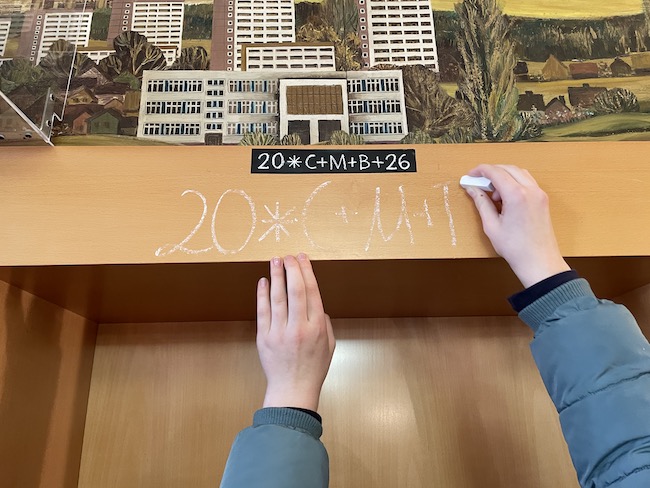 Ein Kind schreibt mit Kreide die Jahreszahl an einen Türrahmen des Rathauses. Die Buchstaben C M B stehen für den lateinischen Segensspruch „Christus mansionem benedicat“ – Christus segne dieses Haus.