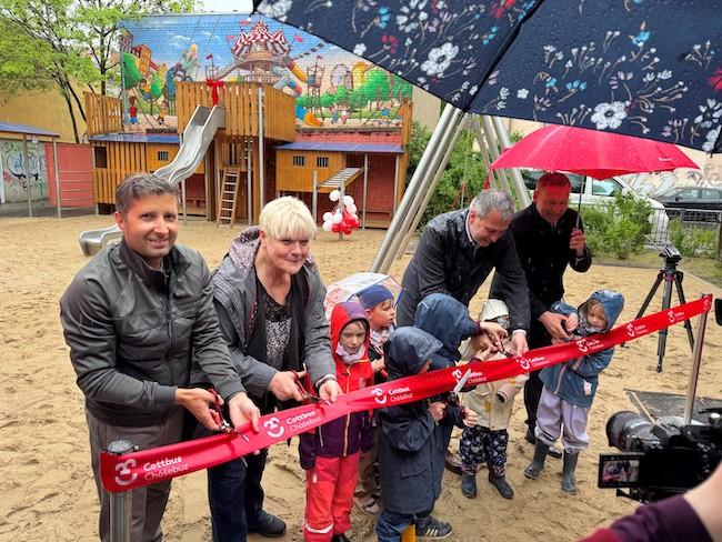 Die Stadtspitze durchschneidet das obligatorische Band zur Eröffnung des Spielplatzes