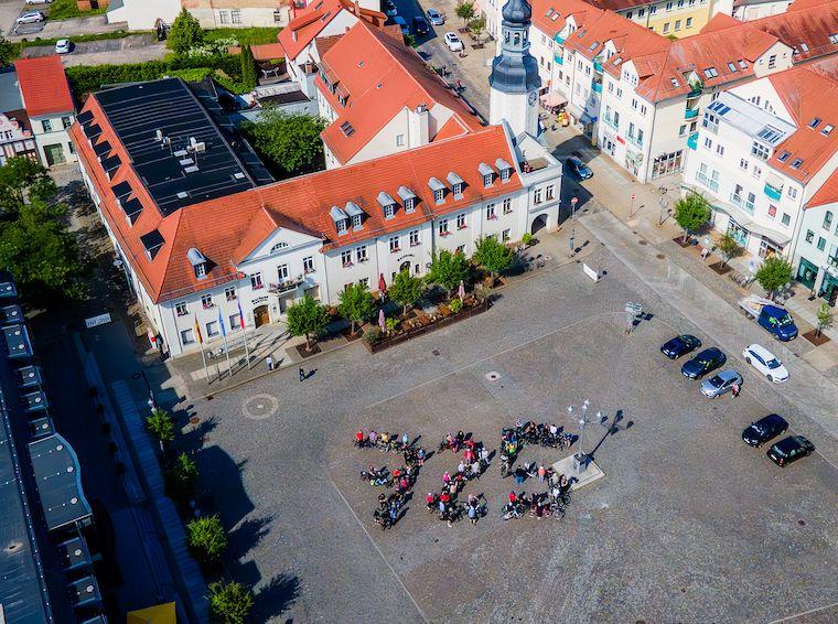 Mit ihren Fahrrädern haben sich Radfahrerinnen und Radfahrer auf dem Spremberger Marktplatz zur Zahl 725 aufgestellt. Mit dieser Foto- Aktion zum 725. Spremberger Stadtjubiläum wurde am 6. Juni 2026 die lokale STADTRADELN-Kampagne eingeläutet. Im Anschluss startete eine geführte Radtour durch das Lausitzer Seenland.