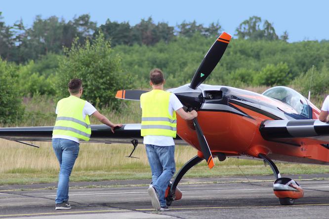 Foto/BU: Mit Blick hinter die Kulissen - Kunstflug besteht nicht nur aus spektakulären Manövern in der Luft. Auch am Boden ist Präzision gefragt: Helfer rangieren das Flugzeug in Position und bereiten den nächsten Einsatz vor.