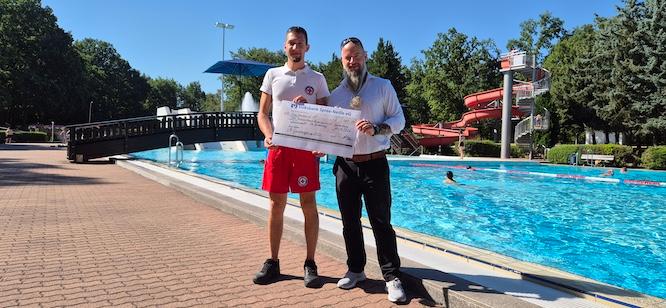 Teamleiter Thomas Schatter (re.) von der Volksbank Spree-Neiße eG überreicht den symbolischen Scheck aus dem VR-Gewinnsparen an den Leiter der Wasserwacht Moritz Zweig (li.)
