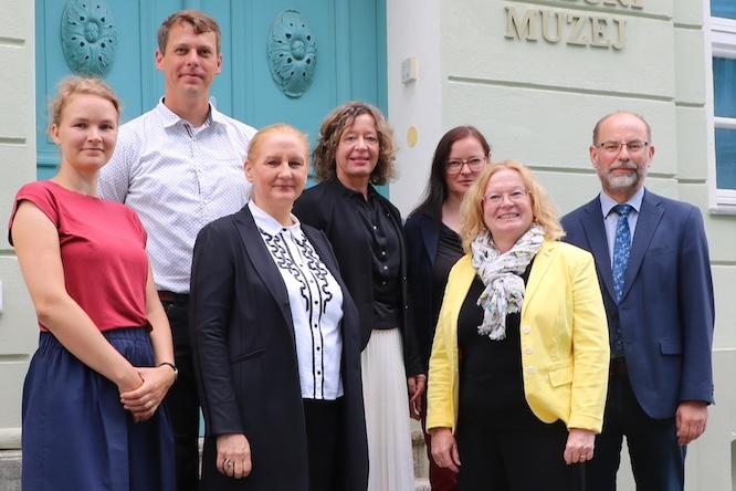 Gemeinsam für das sorbische/wendische Leben in Cottbus/Chóśebuz – Staatssekretärin zum Arbeitsgespräch empfangen Vertreterinnen und Vertreter des Landes Brandenburg haben sich bei einem Besuch in unserer Stadt über die Bedeutung der sorbischen/wen- dischen Sprache und Kultur in Cottbus/Chóśebuz informiert. Dazu be- suchten sie das Wendische Museum und das Wendische Haus. Im Mit- telpunkt standen die Zusammenarbeit von Stadt, Land und Stiftung für das sorbische Volk sowie die weitere Stärkung der sorbischen/wendi- schen Bildungs- und Kulturangebote. Begrüßt wurden die Gäste im Wendischen Museum/Serbski muzej von Eike Belle, Dezernentin für Soziales, Jugend, Bildung und Kultur der Stadt Cottbus/Chóśebuz. Am Austausch nahmen unter anderem Dr. Friederike Haase, Staatssekretärin im Ministerium für Arbeit, Soziales, Gesundheit und Gleichstellung des Landes Brandenburg, sowie Vertreterinnen und Vertreter des Ministeriums für Wissenschaft, Forschung und Kultur, des Wendischen Museums und der Stadtverwaltung teil. Cottbus/Chóśebuz versteht sich als zentraler Ort des sorbischen/wendi- schen Lebens in der Niederlausitz. Als Sitz zahlreicher sorbischer/wendi- scher Institutionen verbindet die Stadt damit eine besondere Verant- wortung für den Erhalt und die Weiterentwicklung von Sprache und Kul- tur. Die Stadt bekennt sich ausdrücklich zum angestammten Siedlungs- gebiet der Sorben/Wenden und legt großen Wert auf gelebte Zweispra- chigkeit im öffentlichen Raum und in der Verwaltung. Die Zusammenarbeit von Stadt, Land und Stiftung zeigt sich auch in der Finanzierung und Unterstützung verschiedener Angebote. Das Wendi- sche Museum wird etwa zur Hälfte durch die Stiftung für das sorbische Volk gefördert. Die Schule für niedersorbische Sprache und Kultur erhält ebenfalls einen wesentlichen Teil ihrer Finanzierung durch die Stiftung, die vom Bund, dem Land Brandenburg und dem Freistaat Sachsen 26. August 2026 Büro des Oberbürgermeisters Ansprechpartner/-in Mary-Ann Basto Neumarkt 5 03046 Cottbus T +49 355 6122007 F +49 355 612132007 mary-ann.basto@cottbus.de Gemeinsam für das sorbische/wendische Leben in Cottbus/Chóśebuz – Staatssekretärin zum Arbeitsgespräch empfangen 2 gefördert wird. Gemeinsam mit der Stiftung unterstützt die Stadt seit 2016 zudem die Stelle einer Jugendarbeiterin der Domowina. Darüber hinaus engagiert sich die Stadt unter anderem mit einem eigenen Stipendium für Lehr- amtsstudierende im Fach Sorbisch/Wendisch, bei der Gestaltung zweisprachiger Elemente im Stadtbild sowie bei Veranstaltungen wie dem „Sorbischen/wendischen Fest - Serbski swěźeń“. Auch die Bildungsangebote zur sorbischen/wendischen Sprache und Kultur in Kitas und Schulen sind ein wichtiges gemeinsames Anliegen; das das Niedersorbische Gymnasium befindet sich in Trägerschaft der Stadt. Das Wendische Museum/Serbski muzej präsentiert in seiner Dauerausstellung die Kulturgeschichte der Sorben/Wenden in der Niederlausitz und gibt Einblicke in Sprache und Literatur, Glaube und Religion, Brauchtum und Tracht, Musik und Bühnenkunst sowie in die Geschichte von Industriali- sierung, Umbruch und dem Verlust von Heimat und Identität. Das Museum ist zugleich Veranstal- tungsort und Sprachraum, unter anderem für die Gesprächsrunde „Serbske blido“. Auch die nächste Sonderausstellung wirft einen besonderen Blick auf die Geschichte der Sor- ben/Wenden in der Region. Vom 11.09.2026 bis zum 21.02.2027 zeigt das Museum die fotografi- sche Ausstellung „Denis Galloway – Gesichter einer Zeit“. Rund 200 historische Glasnegative des schottischen Ethnografen, Fotografen und Künstlers Denis Galloway geben besondere Einblicke in das sorbische/wendische Leben im Spreewald und in der Niederlausitz zu Beginn des 20. Jahrhun- derts. Der regelmäßige Austausch mit den sorbischen/wendischen Gremien und Institutionen hat für die Stadt einen hohen Stellenwert. Ein besonderer Ausdruck dieser Zusammenarbeit ist das alljährli- che Arbeitsgespräch von Oberbürgermeister Tobias Schick mit Vertreterinnen und Vertretern der sorbischen/wendischen Institutionen und Gremien im Wendischen Haus. Der Besuch im Wendischen Museum machte deutlich: Der Erhalt und die Weiterentwicklung der sorbischen/wendischen Sprache und Kultur sind eine gemeinsame Aufgabe. Cottbus/Chóśebuz setzt dabei weiterhin auf eine enge und verlässliche Zusammenarbeit mit dem Land Brandenburg, der Stiftung für das sorbische Volk und den sorbischen/wendischen Institutionen.