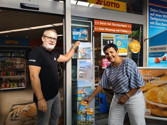 Kathrin Winkler, Geschäftsführerin des Tourismusverbands Lausitzer Seenland und Esso-Tankstelleninhaber Cedric Pietzsch präsentieren den neuen Prospektständer an der Esso Tankstelle in Senftenberg. Reisende erhalten dort ab sofort kostenfreie Informationen und Kartenmaterial zur Urlaubs- und Freizeitregion Lausitzer Seenland.
