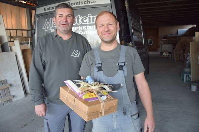 Maurer- und Betonbauermeister Steffen Domisch bedankt sich für die langjährige Zusammenarbeit bei seinem Mitarbeiter Michael Lehmann (r.) mit einem Reisegutschein für die ganze Familie.