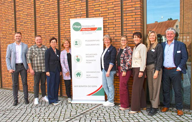 Landrat Marcel Schmidt (l.) und Dezernentin Anja Miersch (3.v.l.) für den Landkreis Elbe-Elster als Träger des Netzwerkes Pflege Elbe-Elster, Chris Behrens von der AOK Nordost (r.) sowie das Team des Pflegestützpunktes, das die Jahresveranstaltung organisiert hatte.